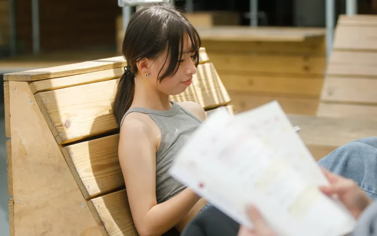 學生坐在木製長椅上閱讀資料
