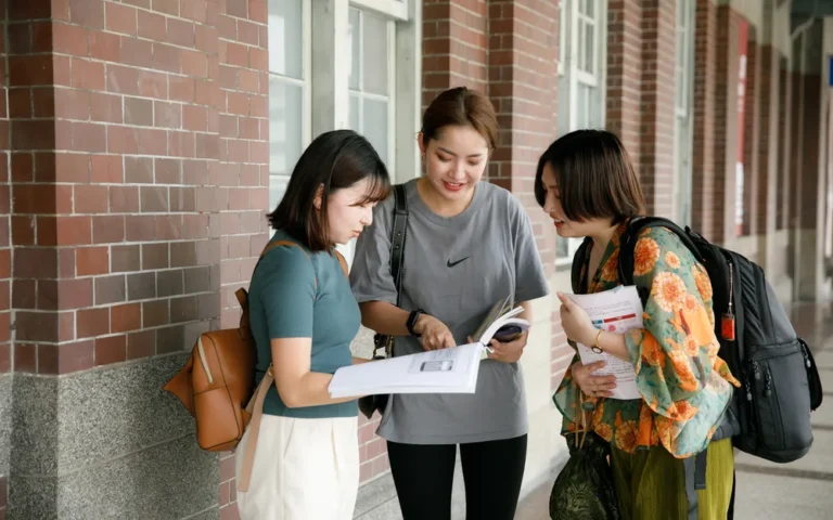 三位學生在紅磚建築前一起翻閱資料